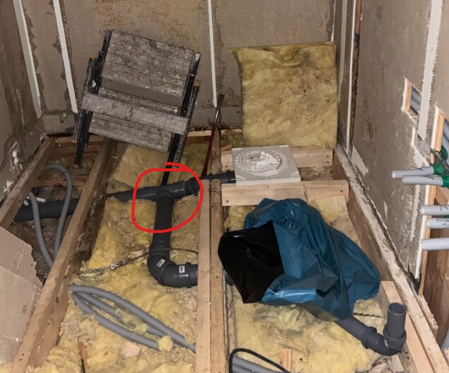 Isolering och rörinstallation under golvkonstruktion i renoveringsprojekt, markerade rör kopplingar tyder på potentiella installationsproblem.