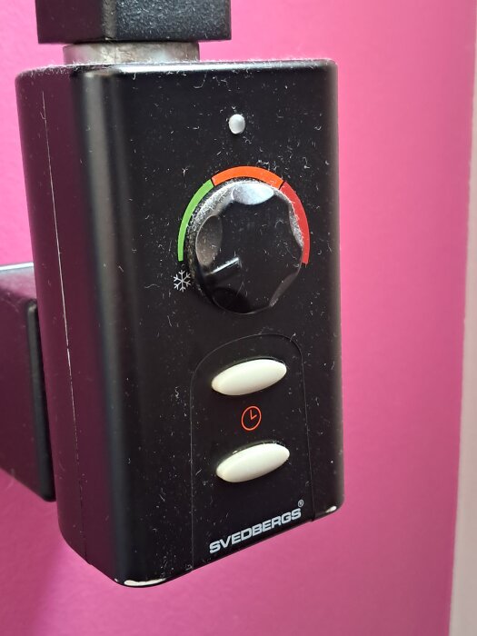 Kontrollpanel från Svedberg med ratt och knappar, monterad på en rosa vägg.