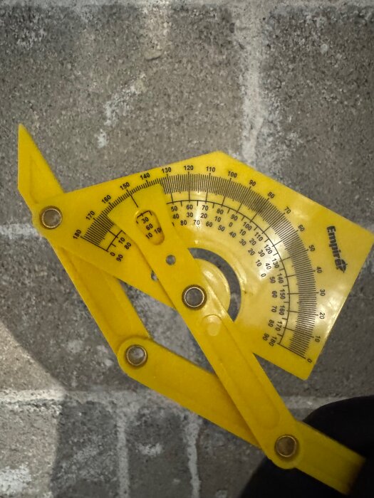 Gul vinkelmätare på betongbakgrund, visar 150 grader.