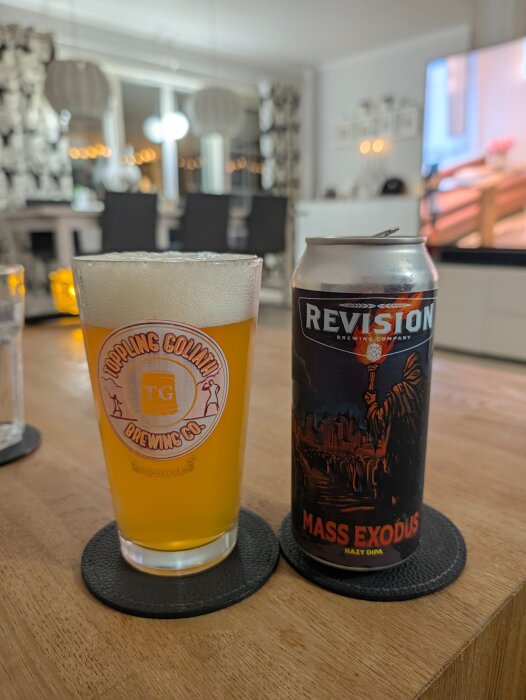 En burk "Mass Exodus" NEIPA och ett glas öl på ett bord i ett vardagsrum.