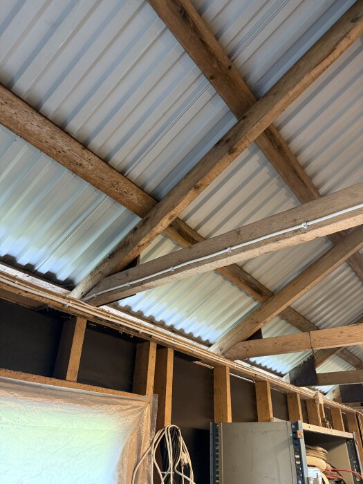 Yttertak av korrugerad plåt med synliga takstolar och isoleringsförberedelser i garage.