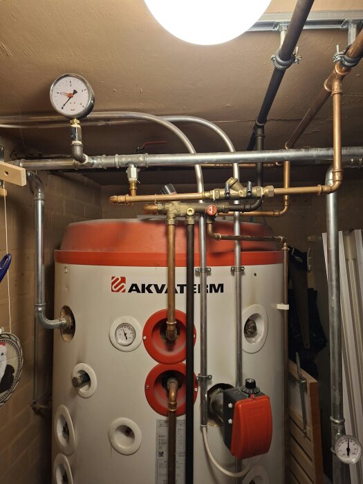 Akvaterm GEO 750 SOLAR värme- och vattensystem med tryckmätare och kopparrör installerat i ett hus, fokus på expansionskärl och ventiler.