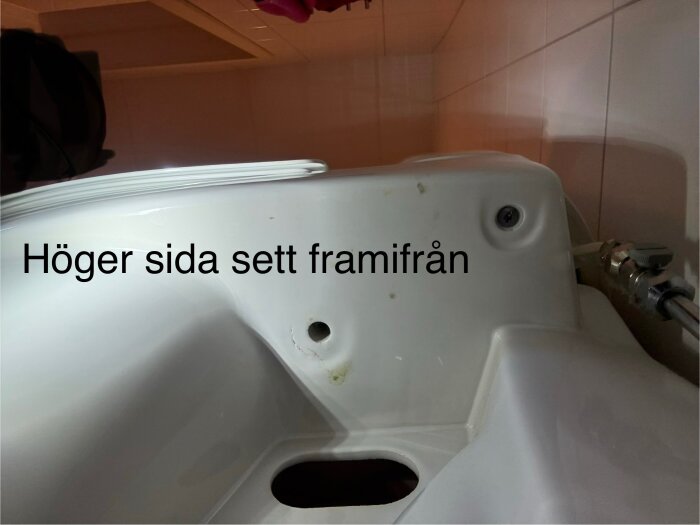 Höger sida av en IDO toalettstol, monterad 2010, med fokus på cistern och stoppventil, text "Höger sida sett framifrån".
