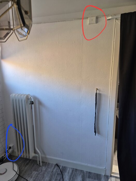 Bild av ett rum med en vägguttagsinstallation markerad i blått vid golvet och en eldosmarkerad i rött nära taket. En radiator syns också.