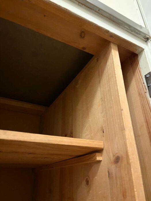 Trämodul med hylla från ett funkiskök, sedd från sidan, ska flyttas för att ge plats åt en diskmaskin.