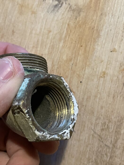 Sprucken radiatorböj i metall som hålls i handen, synlig gänga och vit korrosion påträffas på utsidan.