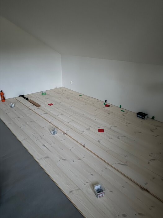 Massivt furugolv nylagt i ett rum under renovering, med verktyg och material synliga på golvet.