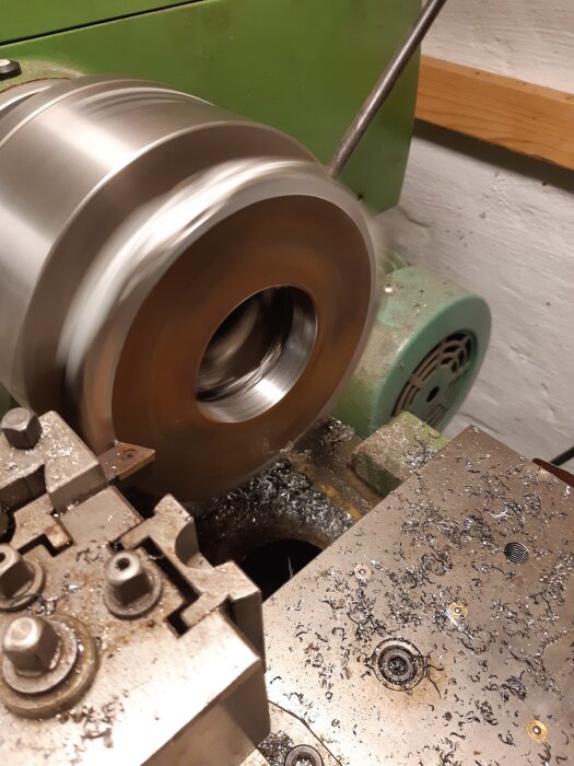 Metallbearbetning på svarv, med en cylinder i snurrande rörelse. Spånor syns på arbetsbänken av svarvprocessen.