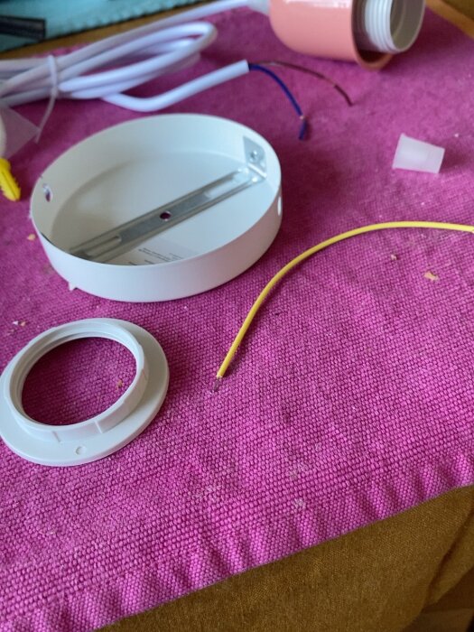 Anslutningssats för lampinstallation med sladdar, kopplingsdosa och tillbehör på en rosa yta.