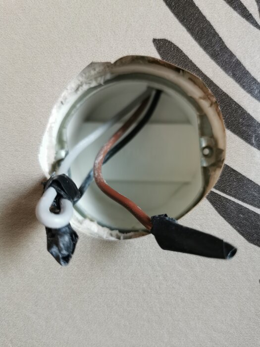 Kabelhål i vägg med bruna, svarta och gråa kablar som sticker ut, redo för installation av en kronbrytare i ett badrum.