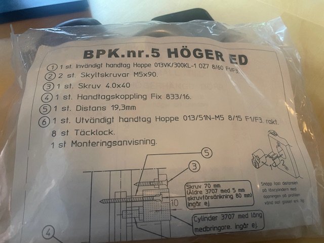 Förpackning med beslagspaket 5 för altandörr, innehållande handtag för insida och utsida, skruvar, distans och monteringsanvisning, märkt "BPK.nr.5 HÖGER ED".