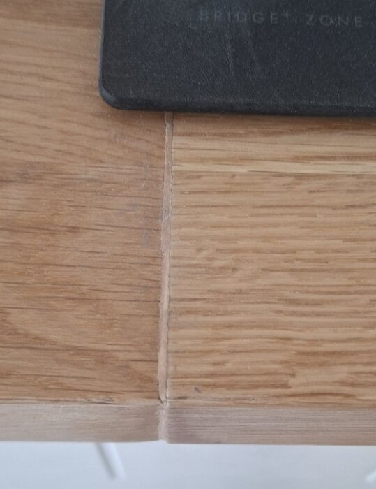 Närbild av två träbänkskivor sammanfogade vid ett hörn, vilket bildar en synlig springa mellan skivorna och oregelbunden yta.