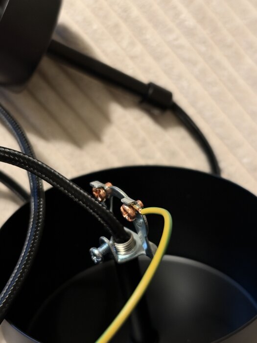 Anslutning av elkabel med metallklämma inuti en svart kopplingsdosa.