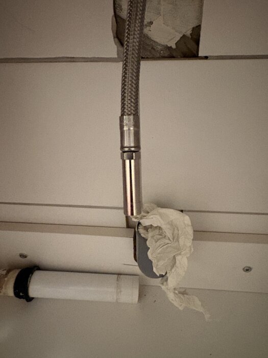 Rörinstallation med en koppling och papper kring rören, visar en osäker tätning mellan 10 mm blandarrör och 12 mm väggkrök.