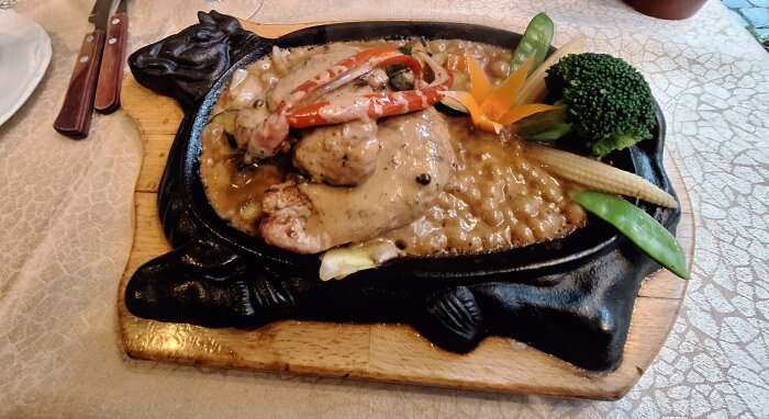 Noisetter med grönpepparsås och potatisgratäng serverade på en koformad tallrik med grönsaker.