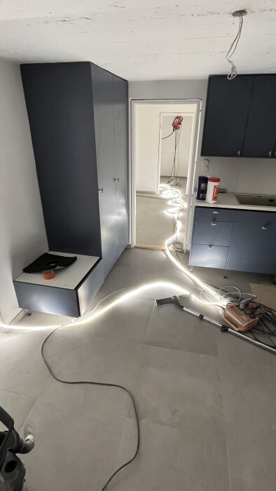 Grå klinkergolv 60x60 cm efter flytspackling, omgivna av mörkblå skåp och verktyg i ett rum under renovering.