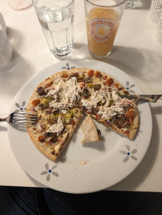 Fryspizza med topping och ett glas dryck på en tallrik.