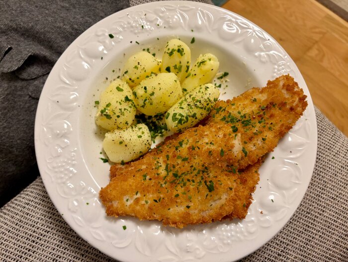 Tallrik med friterad rödspätta täckt av panko och Amandine-potatis toppad med persilja.
