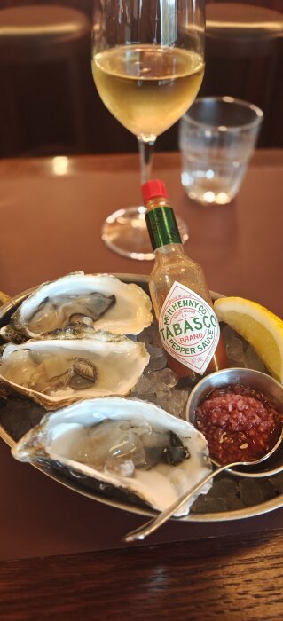 Ostron på is med Tabasco, citronklyfta och röd sås bredvid ett glas champagne.