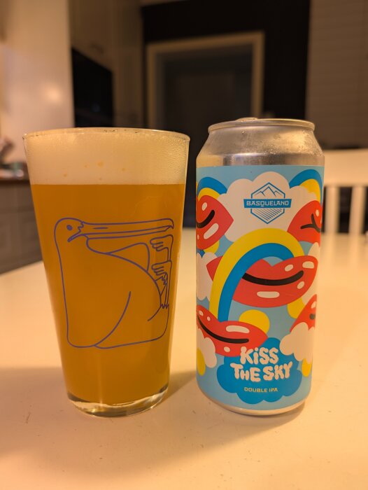 Kopp med öl bredvid en färgglad burk med texten "Kiss the Sky - Basqueland", motiv med regnbågar och läppar.