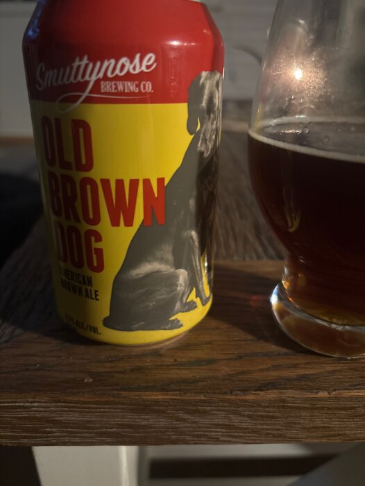 En burk Smuttynose Brewing Co. "Old Brown Dog" American Brown Ale bredvid ett glas med mörk öl på ett bord.