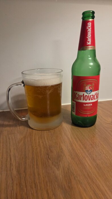Ölglas bredvid en flaska Karlovačko lager på ett träbord.
