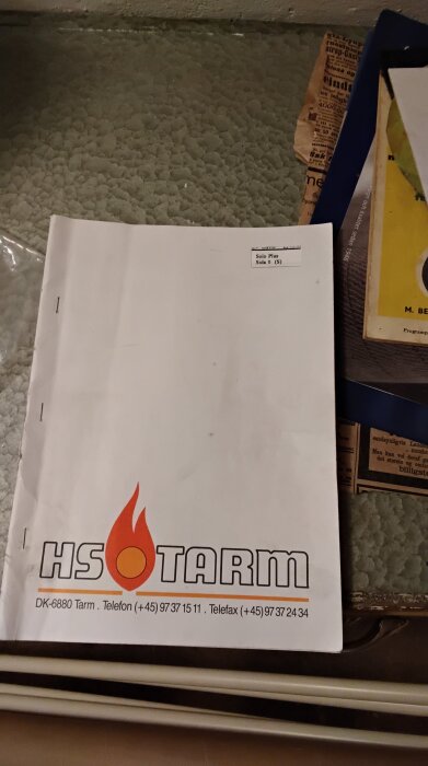 Broschyr från HS Tarm med kontaktinformation och logotyp med orange låga.