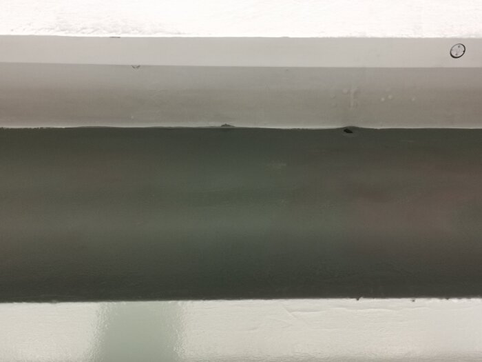Bild av fasad med tydliga hål ovanför skyltfönster i en gammal bybutik från 1938, troligen för ventilation.