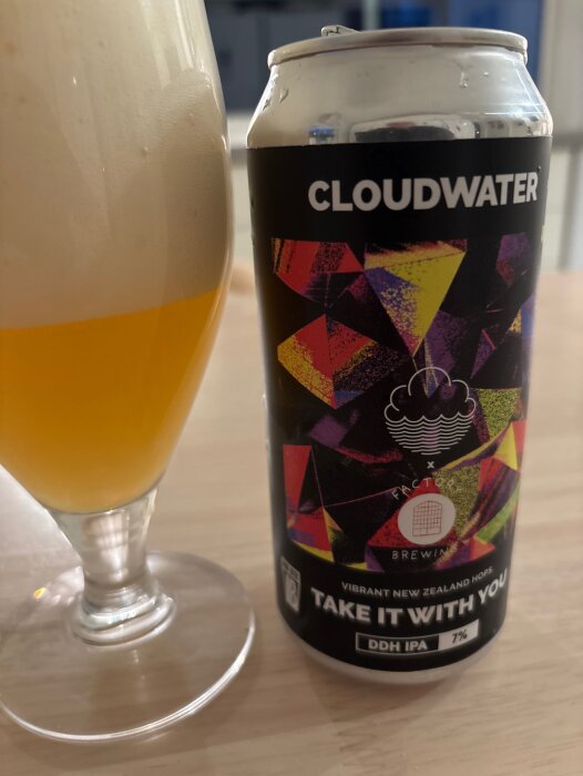 En ölburk med texten "CLOUDWATER" och ett glas öl med stor skumkrona på ett bord.