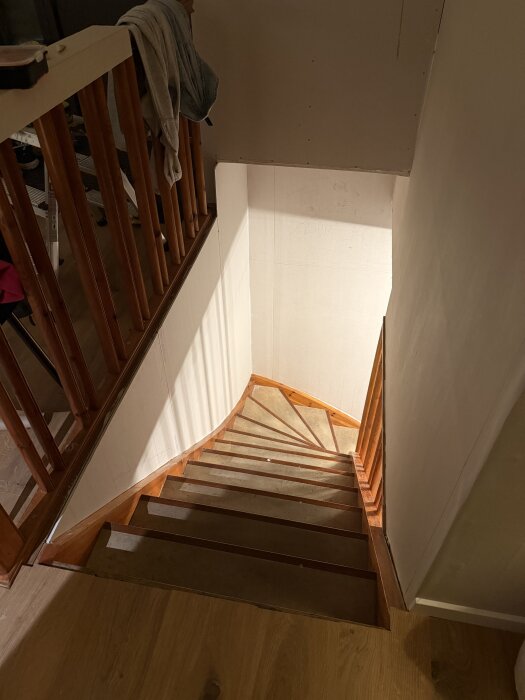 Trappa med nybyggt förråd ovanför och gipsskivor längs väggarna, del av renoveringsprojekt.