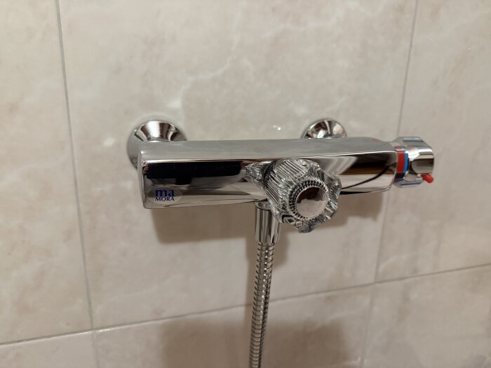 Äldre Mora Term duschblandare som kan läcka från avstängningsvredet, med fokus på ventil och anslutningar, installerad på badrumsvägg.