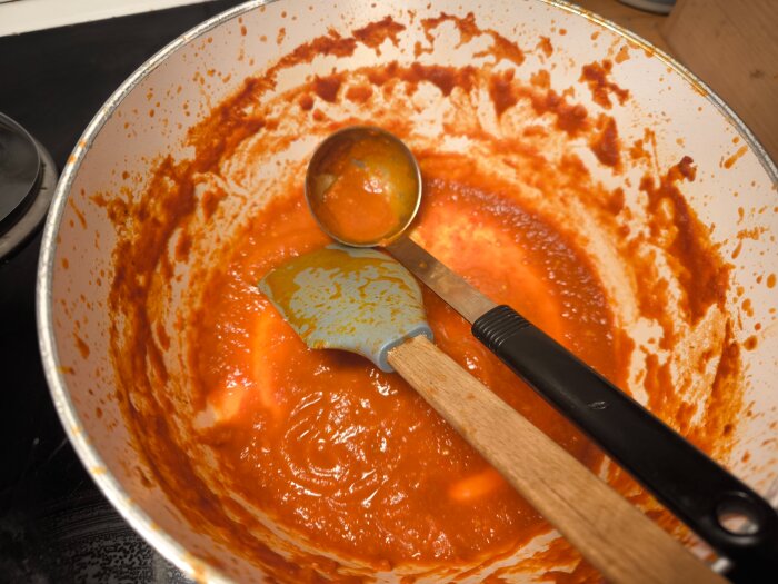 Kastrull med hemkokt chilisås och köksredskap som slev och slickepott.