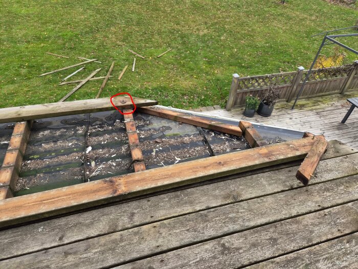 Riven balkong med synliga reglar och plåt, en inringad plats markerar ett stift där en stolpe tidigare stått, omgiven av en gräs- och trädäcksmiljö.