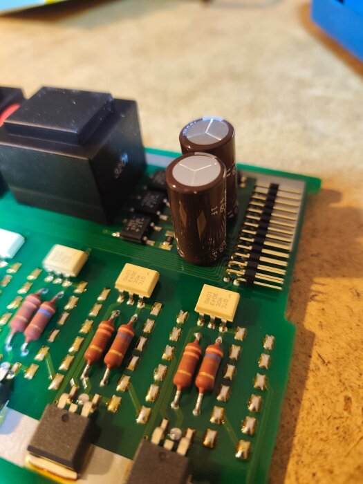 Elektronikkretskort med motstånd, kondensatorer och andra komponenter för ett DIY-larmprojekt med en 12V adapter och Shelly1.