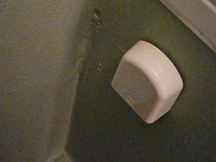 Vitt täcklock på vägg, del av fördelarskåp, inspekteras för korrekt montering enligt Säker Vatten och LK:s riktlinjer.