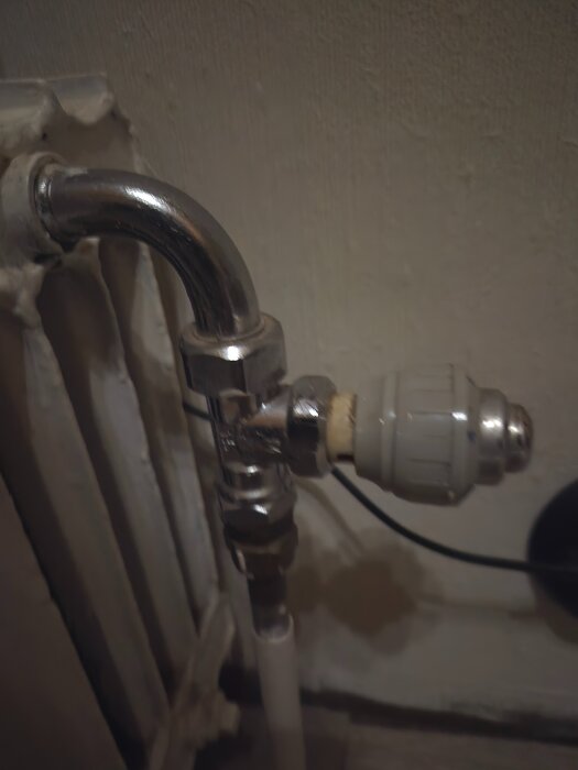 Radiatortermostat monterad på rör vid vägg.