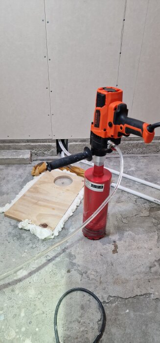 Vevor kärnborrmaskin på betonggolv, borrhål i plywood, rör och XPS-skiva syns i bakgrunden.