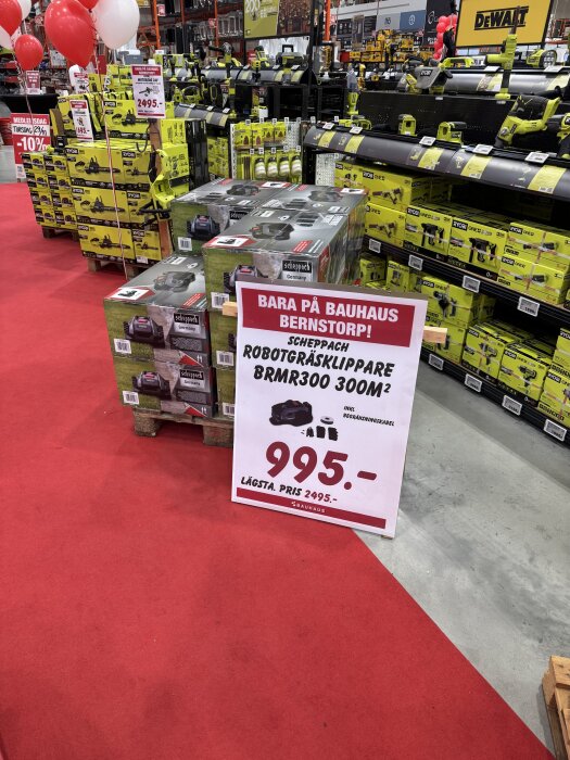 Rea på Bauhaus Bernstorp med robotgräsklippare för 995 kr. Visar rader av verktygsförpackningar och reklam för rabatterade priser i butiken.
