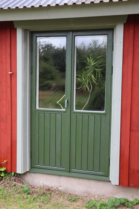 Grön dörr med glasruta, grågrönt foder, röd vägg. Dörren målad med Ottossons linoljefärg, Köpenhamnsgrön nyans.