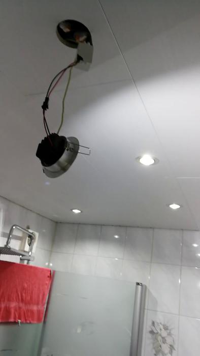 Se processen för att uppgradera belysning med nya spotlights i tak, inklusive borrning av 90mm hål och installation av en 'potta' för dimbar belysning.