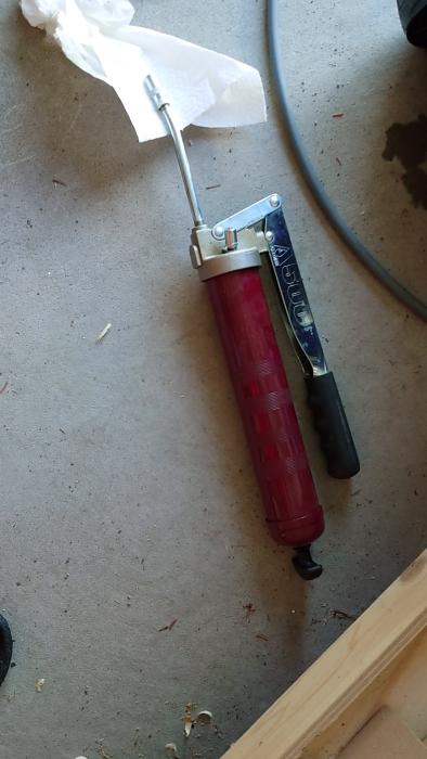 En person använder marint fett för att smörja och underhålla en del av sin utrustning, vilket resulterar i förbättrad funktion och enklare användning.