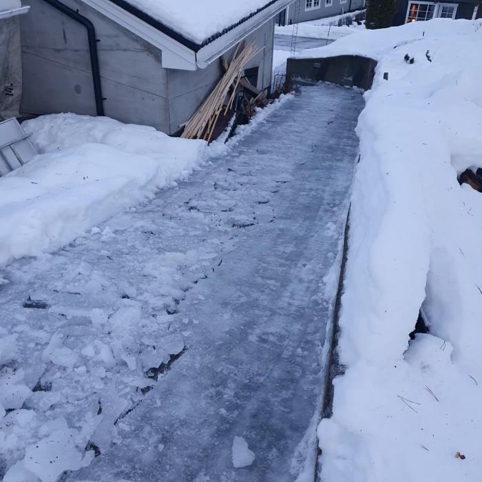 Film på is och snö vid en byggnad, ser ut som nyröjd gångväg eller uppfart.