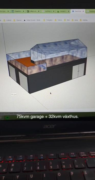 Ett datorgenererat film på en byggnadsmodell visas på en bärbar dators skärm, indikativt för ett garage och växthusprojekt.