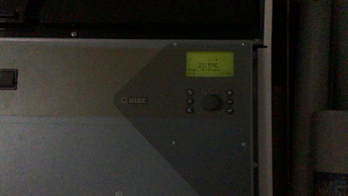 En mörk film som visar en NIBE-enhet med en digital display som anger temperaturen 27,50°C.