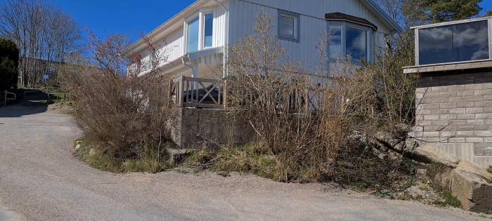 Stenfärgad stödmur med räcke och glas framför ett hus, under en klarblå himmel.