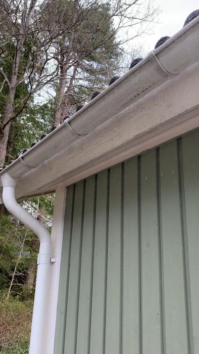 Det är en film av takrännor på ett hus under snöfall mot en grå yttervägg.