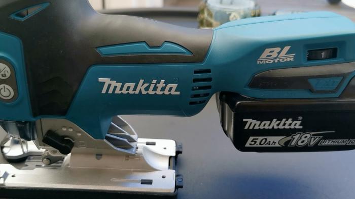 En hand håller en blå Makita slagskruvdragare med ett 5.0Ah 18V batteri.