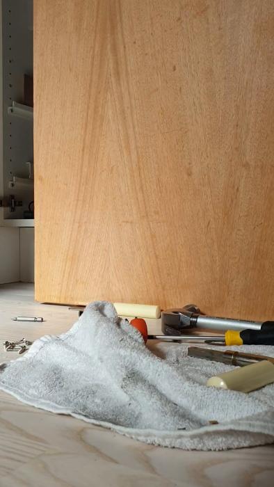 Person installerar en cylinderformad dörrknopp i en dörr, med vita tygstycken i bakgrunden.