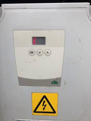 En elskåp med display som visar en felkod, knappar markerade "OK", "V", och "A", och en varningsetikett med en blixt för elektrisk fara.