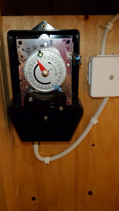 En oskarp film av ett gammalt mätinstrument eller ur med visare och skala, monterat på ett mönstrat kretskort eller panel.